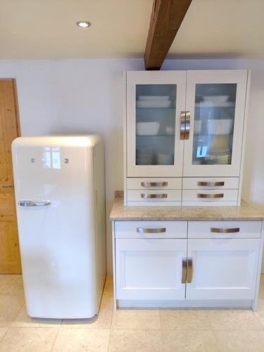 a kitchen with white cabinets and a white refrigerator at Spacious Ski Chalet In Traditional French Village, sleeps 8, Four Star with fibre broadband in Abondance