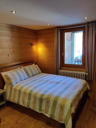 a bedroom with a large bed with a window at Spacious Ski Chalet In Traditional French Village, sleeps 8, Four Star with fibre broadband in Abondance