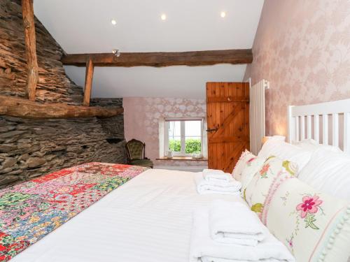 a bedroom with a bed with a stone wall at Jacky Garth Cottage in Keswick