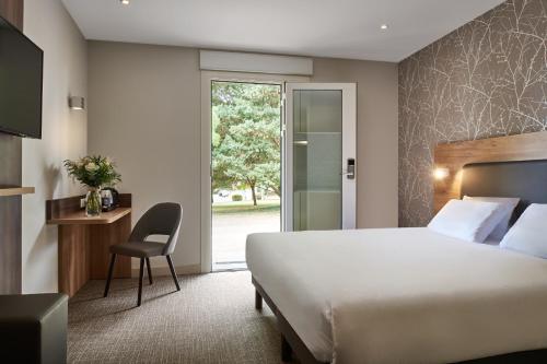Habitación de hotel con cama y silla en Kyriad Sens en Sens