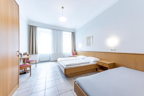 Habitación de hotel con 2 camas y escritorio en Pension Fünfhaus, en Viena