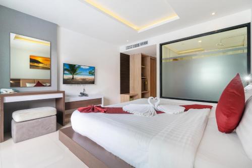 1 dormitorio con 1 cama blanca grande con almohadas rojas en Paripas Patong Resort - SHA Extra Plus, en Patong Beach