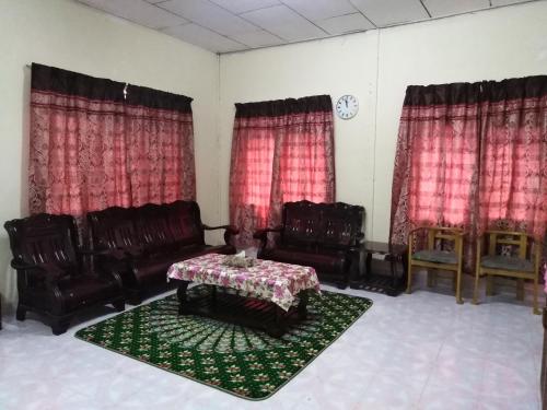 a living room with leather chairs and a table and red curtains at Homestay Haji Hamid in Pantai Cenang