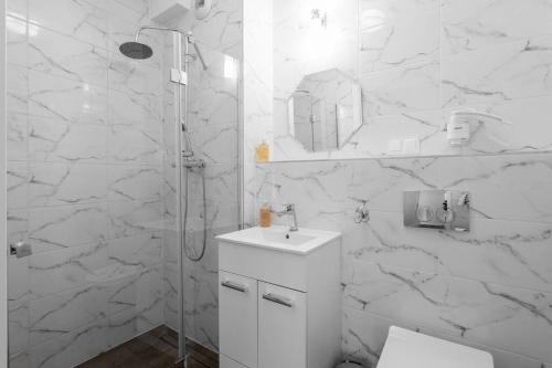 a white bathroom with a sink and a shower at GRANO FLATS Sobieszewo - Villa Neptun in Sobieszewo