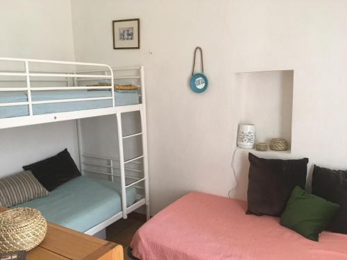 Cette petite chambre comprend des lits superposés et un canapé. dans l'établissement La Maison et son adorable jardin clos, à Porquerolles