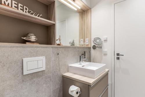 W łazience znajduje się umywalka i lustro. w obiekcie NEU! Exklusives Apartment Turmkoje im Herzen Westerlands w mieście Westerland