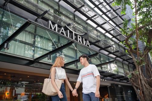 a man and a woman standing in front of a building at Maitria Hotel Sukhumvit 18 Bangkok – A Chatrium Collection in Bangkok