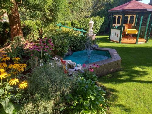 a garden with a small pool and a gazebo at Schedlers Löwenhotel-GARNI in Alberschwende