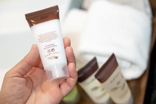 a hand holding a bottle of moisturizing moisturizing moisturizing fluoride toothpaste at Maitria Hotel Sukhumvit 18 Bangkok – A Chatrium Collection in Bangkok