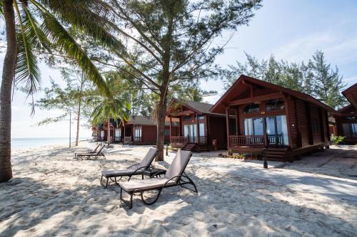 a couple of chairs on the beach in front of a resort at Sutera at Mantanani Island Resort & Spa in Mantanani Island 