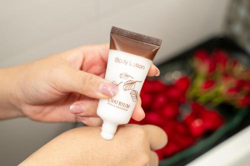 a person holding a bottle of baby activation cream in front of flowers at Maitria Hotel Sukhumvit 18 Bangkok – A Chatrium Collection in Bangkok