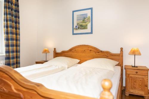 - une chambre avec un lit en bois et des draps blancs dans l'établissement Ferienwohnung "Strandkorb", à Hinrichsdorf