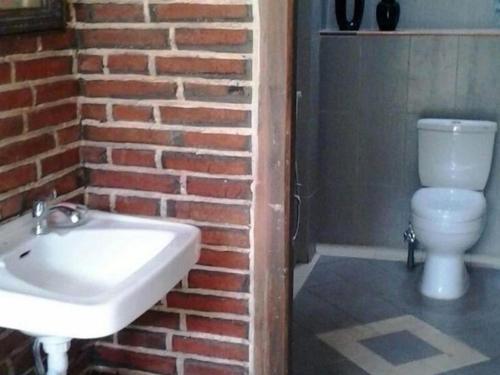 La salle de bains est pourvue d'un lavabo blanc et d'un mur en briques. dans l'établissement villas in batu indonesia homestay, à Kotalama