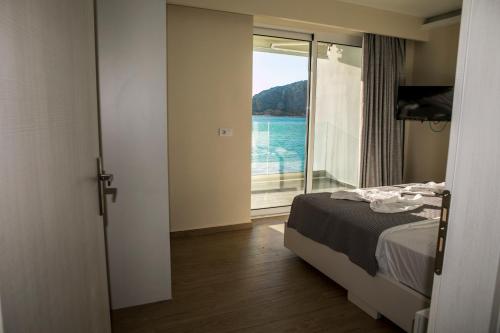 Schlafzimmer mit einem Bett und Blick auf das Wasser in der Unterkunft HOTEL ALEXANDER in Mýtikas