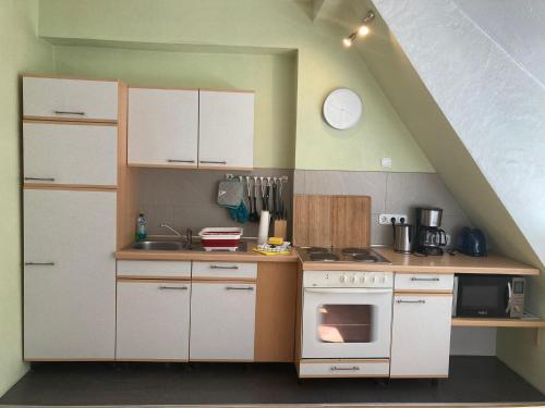 a small kitchen with white cabinets and a stove at Dorfschule Mollseifen in Winterberg