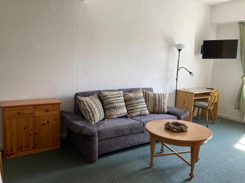 a living room with a blue couch and a table at Dorfschule Mollseifen in Winterberg