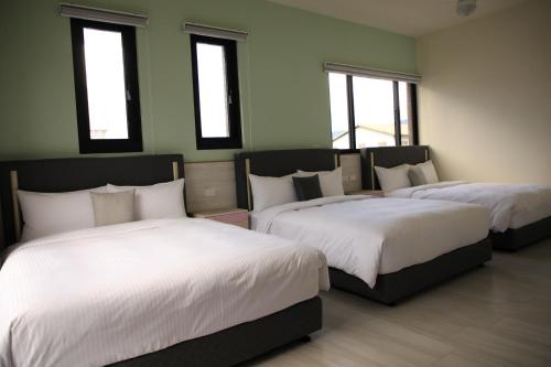 a room with three beds with white sheets and windows at Guan Shan Pavilion in Guanshan