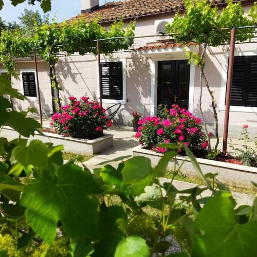 a white house with pink flowers in front of it at Kuća Lilla in Loborika