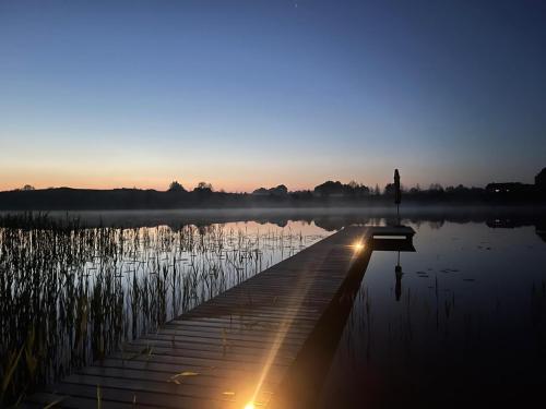 a person standing on a dock near a body of water at Pineplace in Joniškis