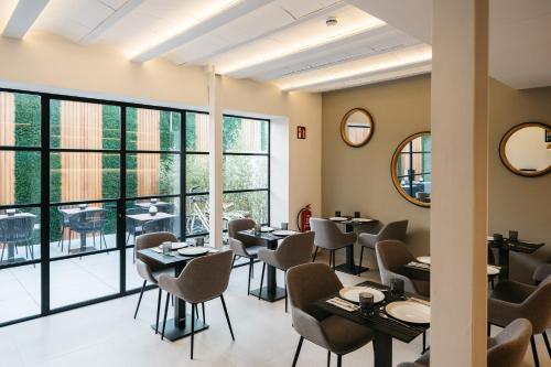 um restaurante com mesas e cadeiras e janelas grandes em Boutique Hotel Petit Montisión em Palma de Maiorca