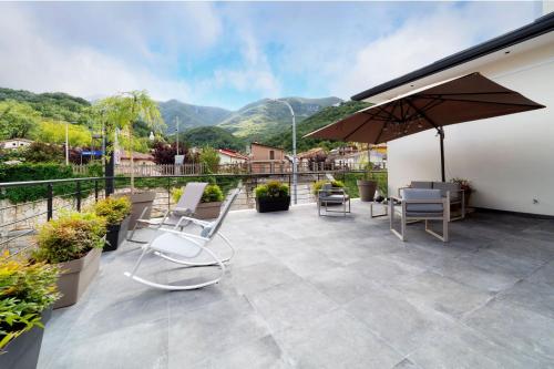 a patio with chairs and an umbrella and mountains at The Garden in Canistro