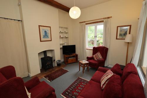 a living room with a red couch and a fireplace at Spixworth Hall Cottages in Spixworth