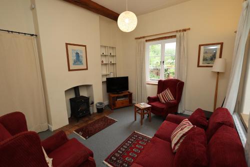 ein Wohnzimmer mit einem roten Sofa und einem Kamin in der Unterkunft Spixworth Hall Cottages in Spixworth