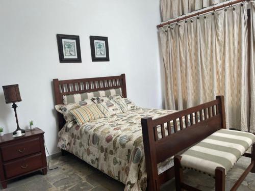 a bedroom with a bed and a chair and curtains at VILLA CON Piscina en Juan Dolio in La Guáyiga