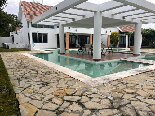 a house with a swimming pool with a pergola at VILLA CON Piscina en Juan Dolio in La Guáyiga