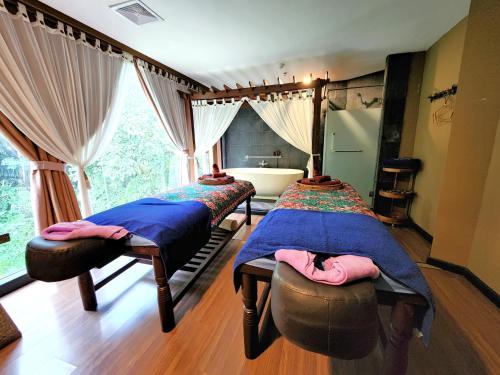 two beds in a room with a tub and a window at The Palace Hotel Kota Kinabalu in Kota Kinabalu