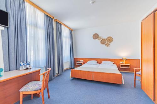 ein Hotelzimmer mit einem Bett, einem Tisch und Stühlen in der Unterkunft Hôtel Le Petit Poète in Echternach