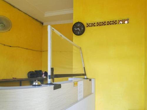 a yellow wall with a clock on a wall at De Luck Homestay near Alun Alun Sidoarjo in Sidoarjo