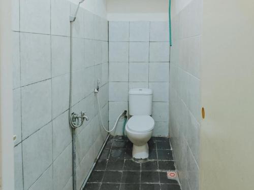 a bathroom with a toilet in a tiled room at De Luck Homestay near Alun Alun Sidoarjo in Sidoarjo