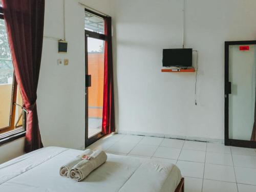 a room with a bed and a tv and a window at De Luck Homestay near Alun Alun Sidoarjo in Sidoarjo