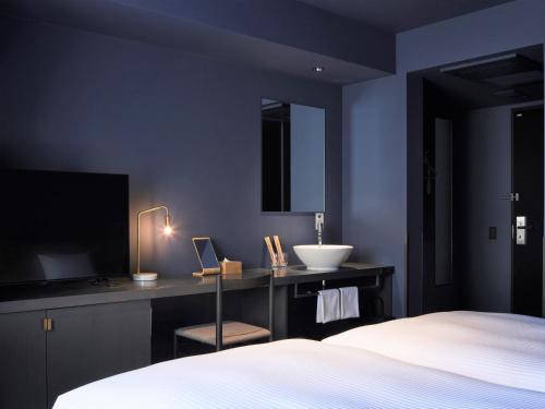 1 dormitorio con cama, lavabo y TV en hotel androoms Sapporo Susukino, en Sapporo