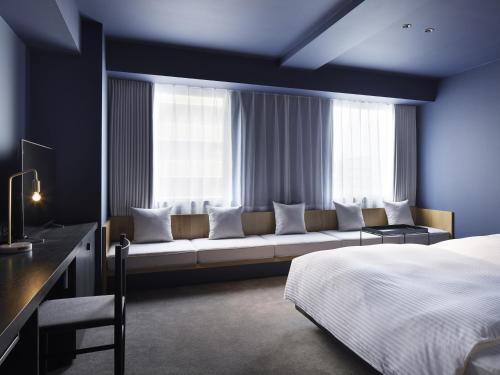 a bedroom with a couch in front of a window at hotel androoms Sapporo Susukino in Sapporo