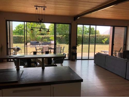 un grand salon avec une table et une terrasse dans l'établissement Villa des 3 chênes, à Plouénan