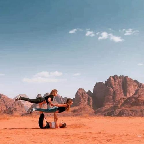 a man and a woman standing on a surfboard in the desert at Harmony Luxury Camp in Wadi Rum
