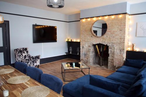 ein Wohnzimmer mit einem blauen Sofa und einem Kamin in der Unterkunft Luxury 3 Bed Apartment in the Heart of Stamford in Lincolnshire