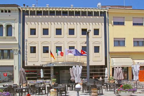 un bâtiment avec des tables et des drapeaux devant lui dans l'établissement HR Hotel, à Monfalcone