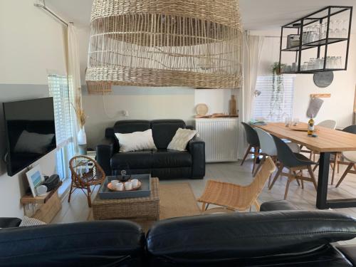 a living room with a black couch and a table at "ZeeLandZon" Holiday home by the lake with Jacuzzi and Sauna in Herkingen