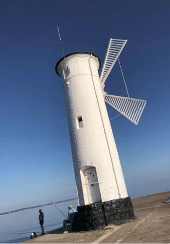 a white lighthouse with a windmill on the beach at Swinoujscie Poland Luxury Penthouse Sleeps 9 in Świnoujście