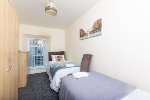 a small bedroom with two beds and a window at Sandfields House in Gorseinon