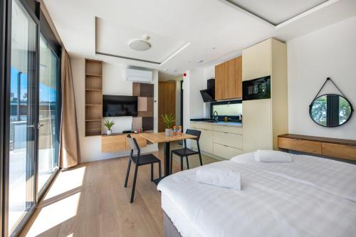 a bedroom with a bed and a table and a kitchen at H55 in Balatonlelle