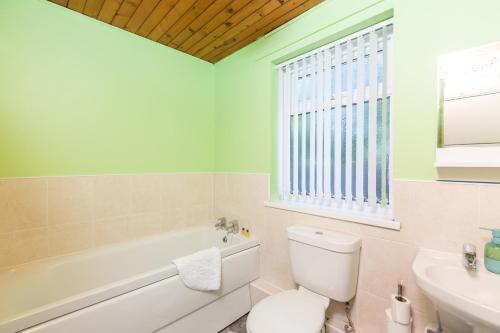 a bathroom with a toilet and a tub and a sink at Sandfields House in Gorseinon