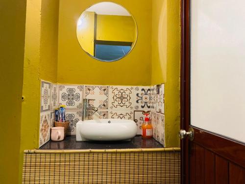 Baño amarillo con lavabo y espejo en Wooden House 38 Hang Cot - 5' to HoanKiem Lake & Al Noor Mosque, en Hanói