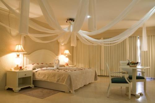 a bedroom with a white bed with drapes at Excelaris Grand Resort Conventions & Spa in Tequesquitengo