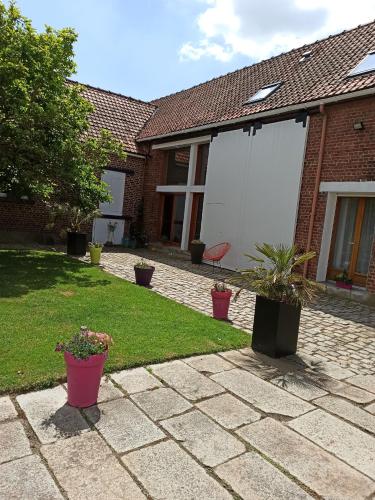 a patio with potted plants and a house at L'Heure Bleue gîtes et chambres d'hôtes in Givenchy-en-Gohelle