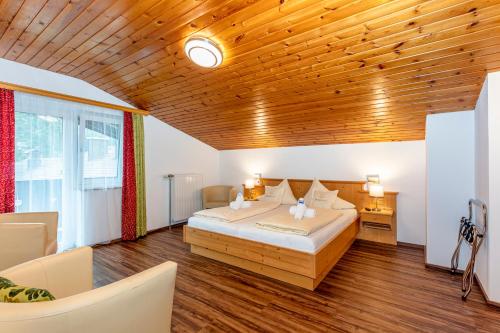 a bedroom with a bed and a wooden ceiling at Frühstückshotel Birkenhof in Rauris