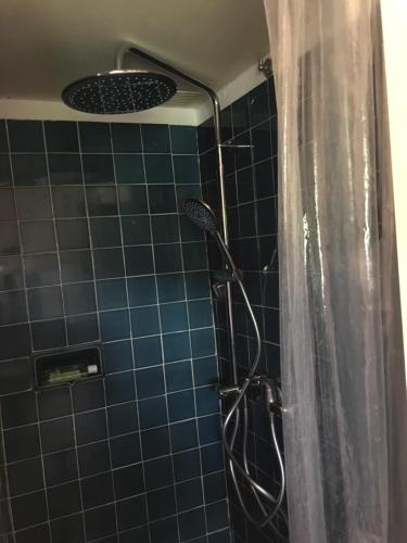 La salle de bains est pourvue d'une douche et d'un mur en carrelage bleu. dans l'établissement La Maison et son adorable jardin clos, à Porquerolles